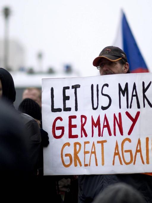 Ein Demonstrant der Bergida-Bewegung, einem Ableger von Pegida, hält ein Plakat mit der Aufschrift "Let us make Germany great again" am Hauptbahnhof im Regierungsviertel in Berlin.