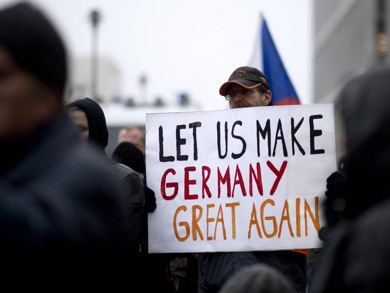 Ein Demonstrant der Bergida-Bewegung, einem Ableger von Pegida, hält ein Plakat mit der Aufschrift "Let us make Germany great again" am Hauptbahnhof im Regierungsviertel in Berlin.