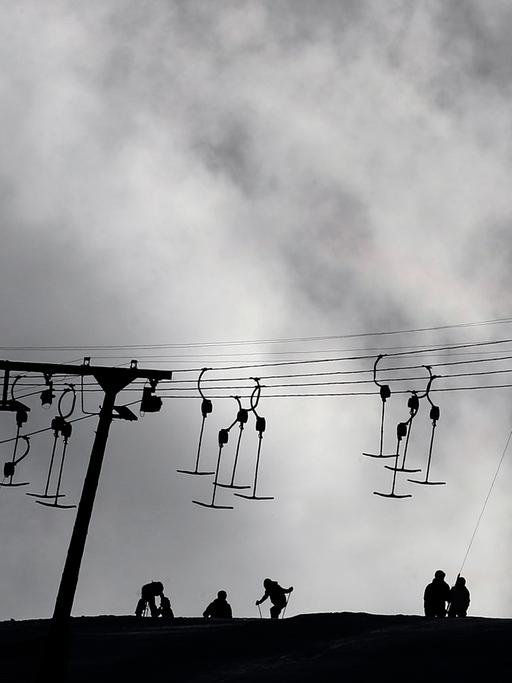 Wintersportler und ein Schlepplift zeichnen sich am 01.02.2014 am Sudelfeld bei Bayrischzell (Bayern) als Schattenriss vom Himmel ab.