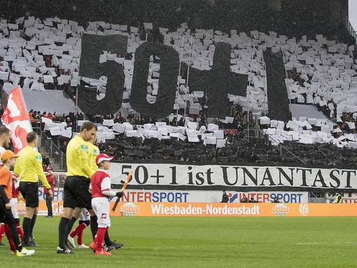 Choreografie in einem Stadion mit den übergroßen Zeichen 50+1 und einem Banner mit der Aufschrift "50+1 ist unantastbar!"