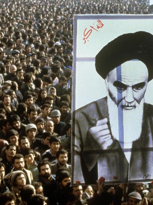 Iranische Bürger protestieren im Jahr 1979 gegen den Schah. Im Vordergrund ist ein riesiges Banner mit dem Abbild von Revolutionsführer Ruhollah Khomeini