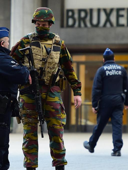 Ein Polizist und ein schwer bewaffneter Soldat unterhalten sich vor dem Brüsseler Hauptbahnhof am 22.03.2016.