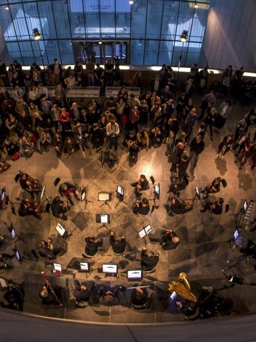 Eröffnung der Ausstellung "Peace Is Power" von Yoko Ono im Museum der bildenden Künste Leipzig. Die Kamera blickt von oben auf das Publikum und ein Orchester während der Eröffnungsveranstaltung, 2019.