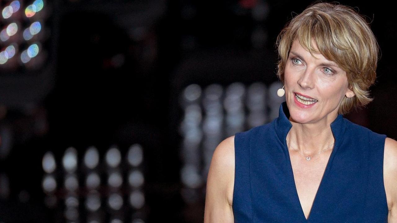 heute journal-Moderatorin Marietta Slomka vor einem schwarzen Hintergrund mit einem Ansteckmikrofon.