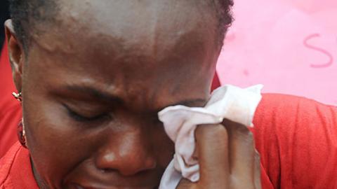 Die Mutter eines der entführten Mädchen wischt sich mit einem Taschentuch die Tränen aus den Augen.