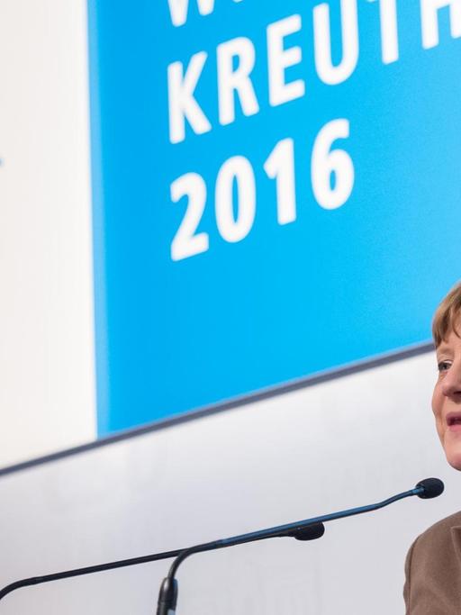 Bundeskanzlerin Angela Merkel in Kreuth. Sie spricht in ein Mikrofon am Rednerpult und lacht.