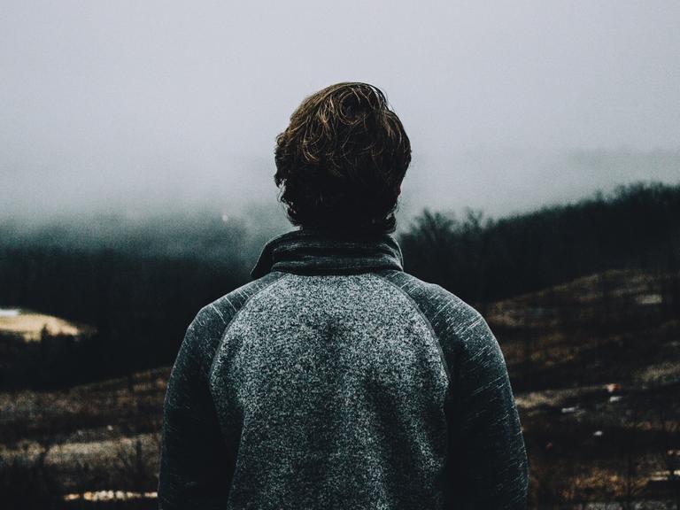 Ein Mann blickt auf eine nebelige Landschaft.