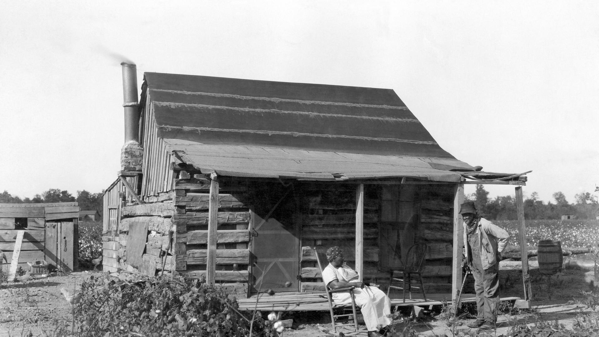 Sklaven im Jahre 1895 vor ihrer Hütte auf einem Baumwollfeld.