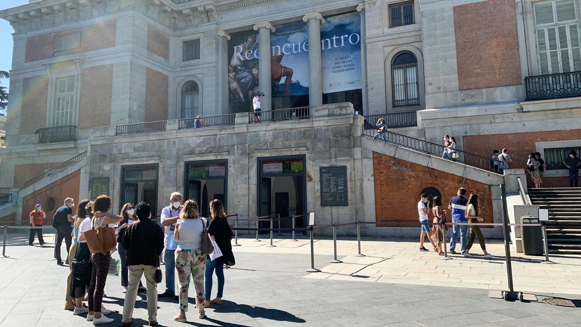 Spanien, Madrid: Menschen tragen Nasen-Mund-Schutzmaske vor dem Eingang des Prado Museums