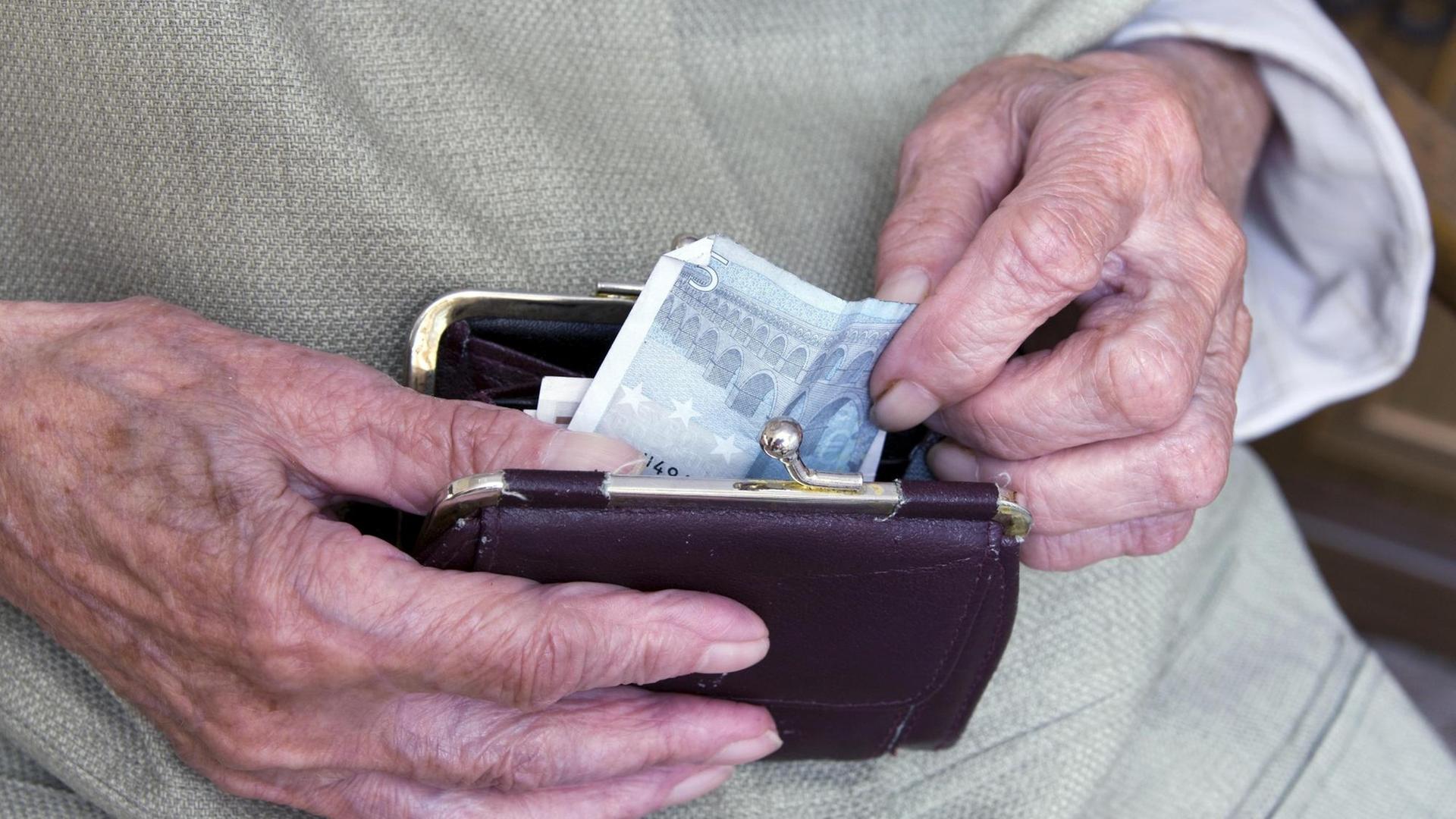 Eine alte Dame holt einen Geldschein aus ihrer Börse Eine alte Dame holt einen Geldschein aus ihrer Börse