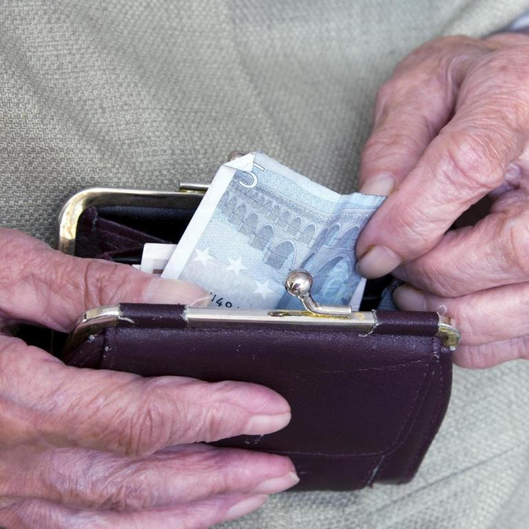 Eine alte Dame holt einen Geldschein aus ihrer Börse