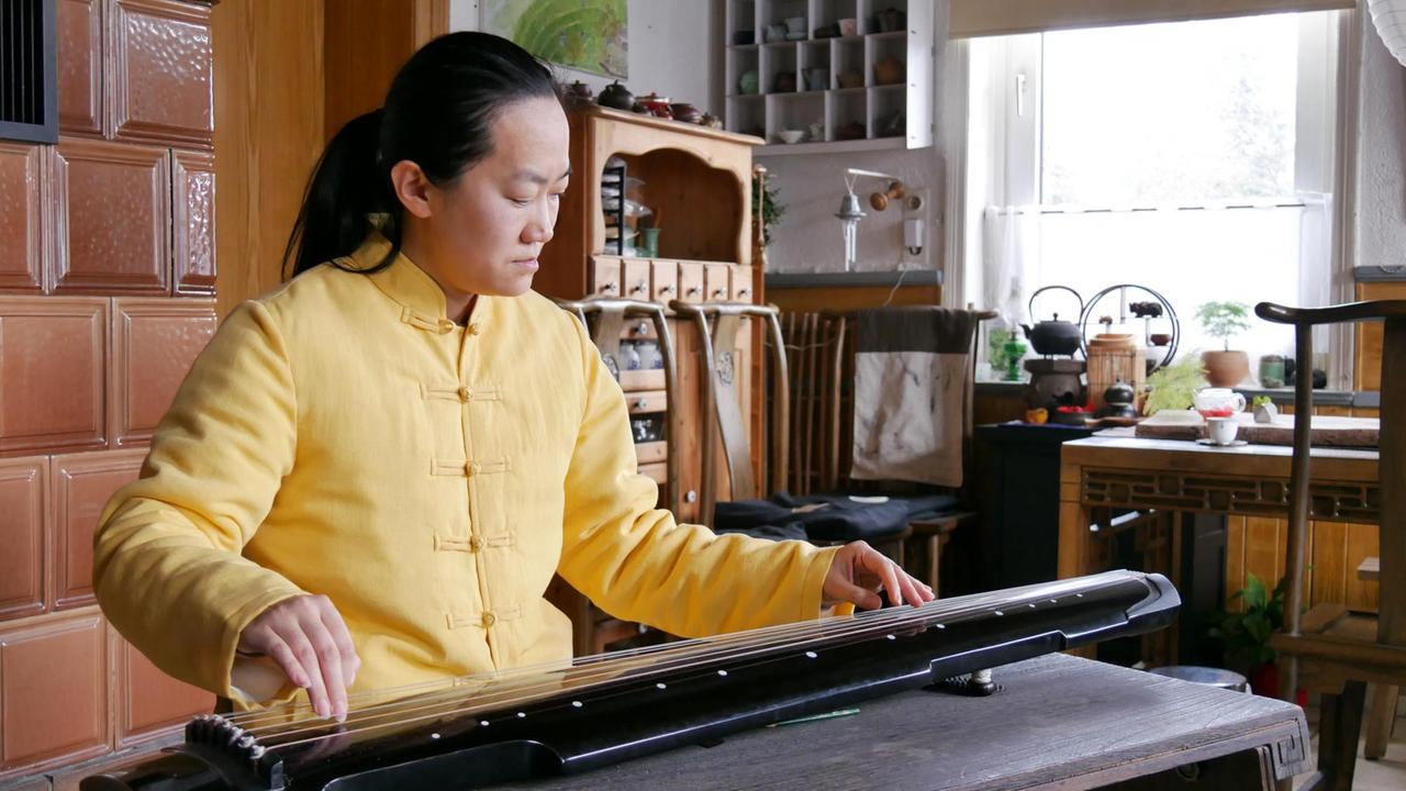 Wenzhuo Liu spielt traditionelle daoistische Musik auf einer Zither