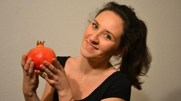 Deniz Julia Güngör hat "Feinsprecher" gegründet, Sprach-Kochkurse in Berlin, sie hält einen Granatapfel in der Hand