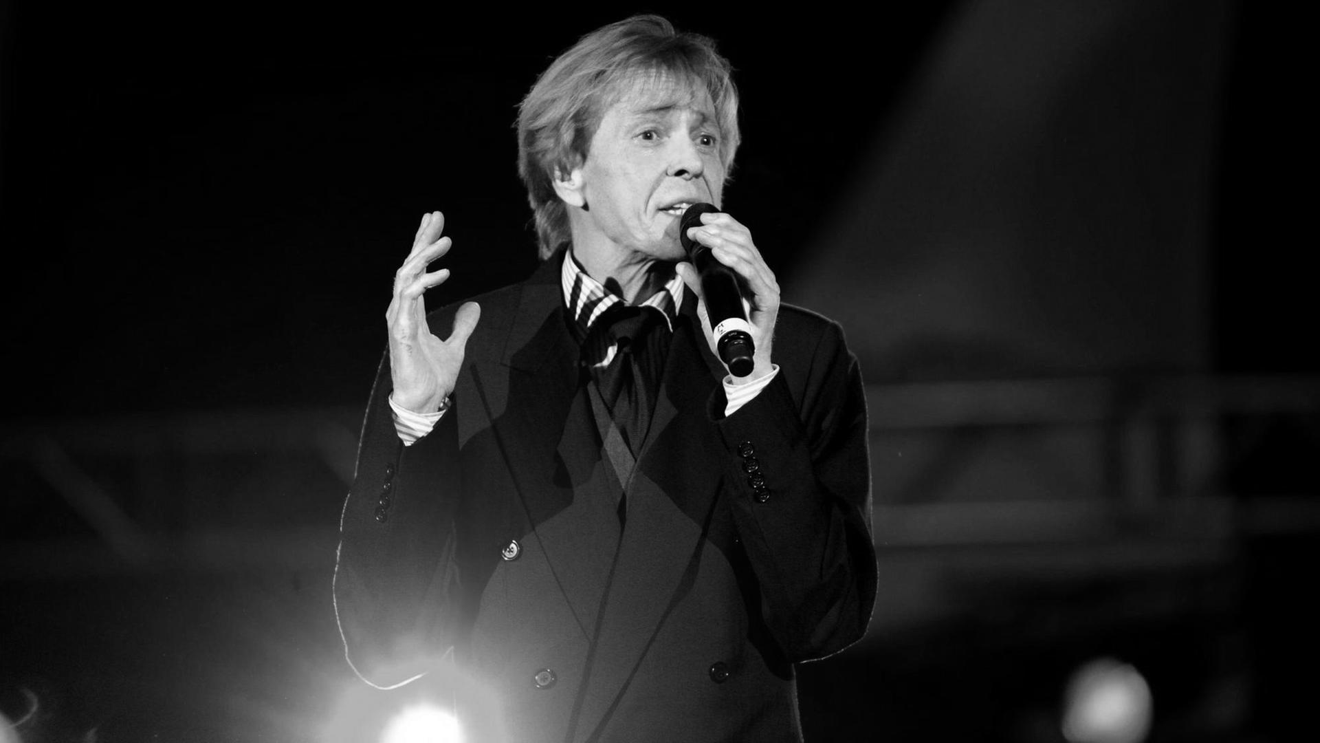 Schlager-Star Jürgen Marcus singend, mit Mikrofon in der Hand und von Scheinwerfern beleuchtet