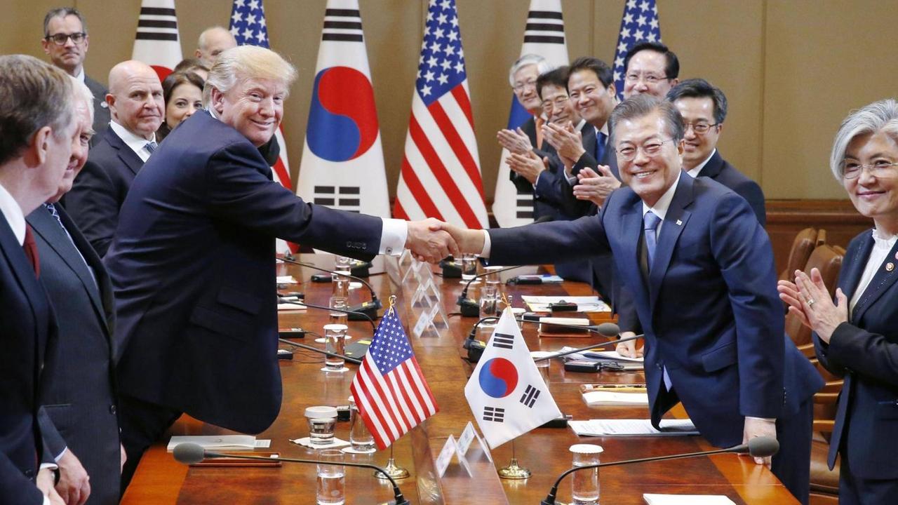 Trump und Moon stehend am Konferenztisch, schütteln die Hände.