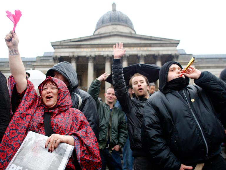Demonstranten feiern in London am 13.04.2013 am Trafalgar Square den Tod von Margaret Thatcher. Sie winken und blasen auf Spielzeugtröten.