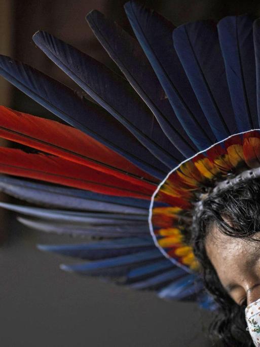 Eine Indigena in Brasilien mit einem Mundschutz und mit dem Kopfschmuck des Sateré-Mawé Volkes