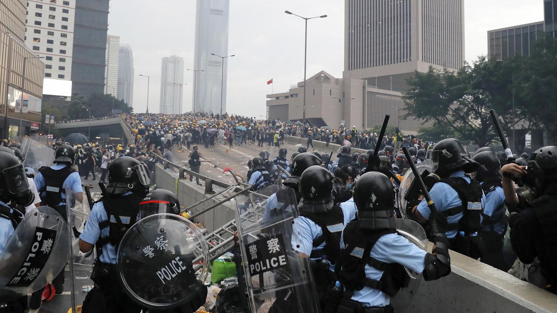 Die Bereitschaftspolizei in Hongkong versammelt sich in der Nähe des Parlaments in Hongkong, im Hintergrund sind Demonstranten zu sehen.