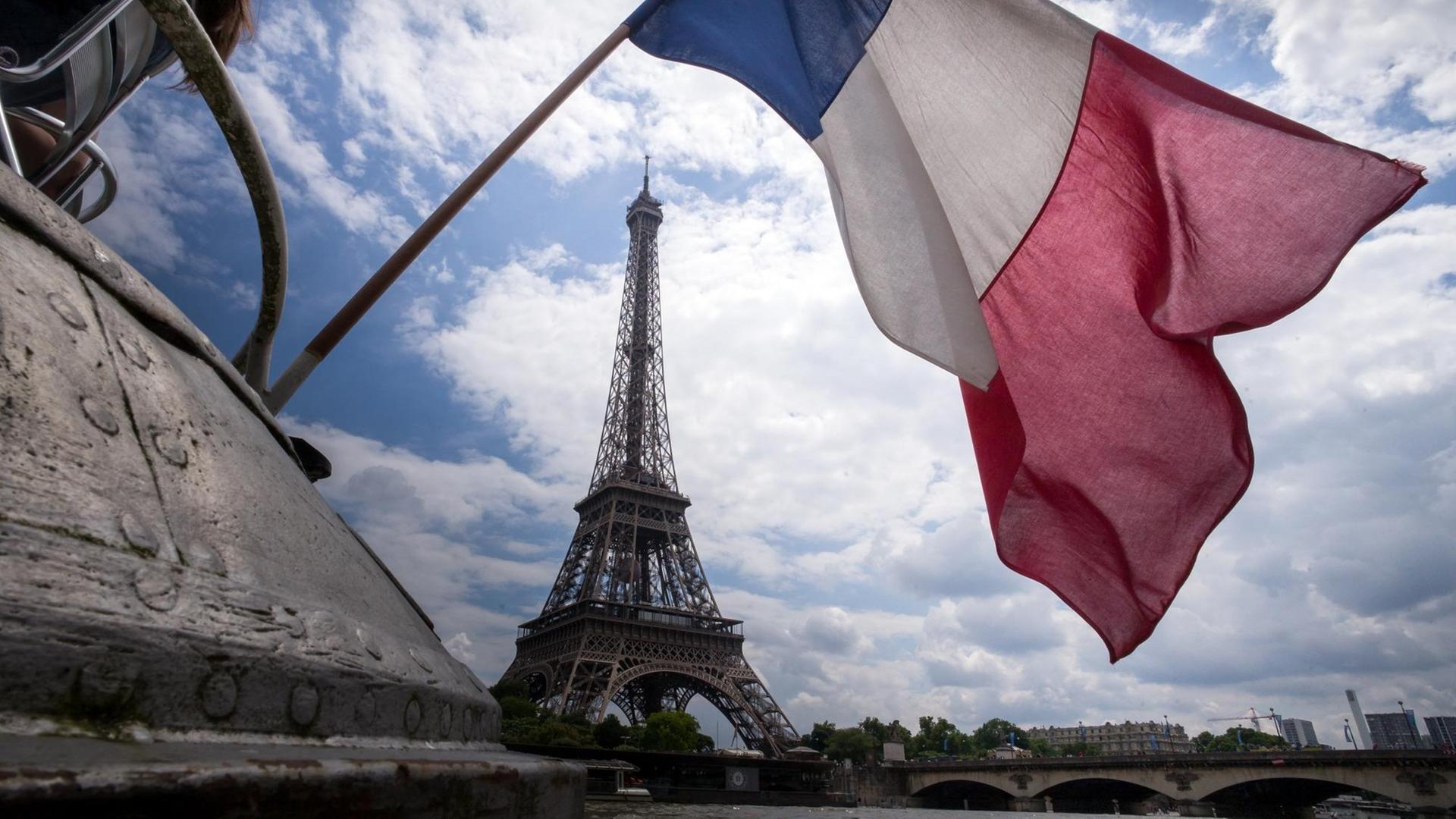 Eine französische Flagge weht vor dem Eiffelturm in Paris.