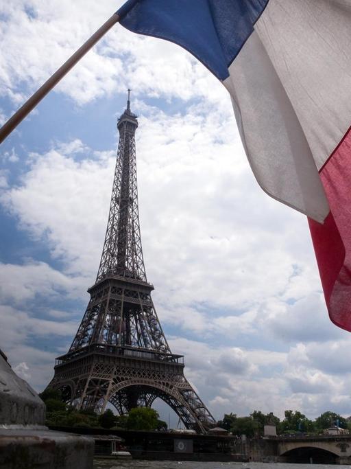 Eine französische Flagge weht vor dem Eiffelturm in Paris.