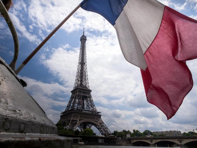 Eine französische Flagge weht vor dem Eiffelturm in Paris.