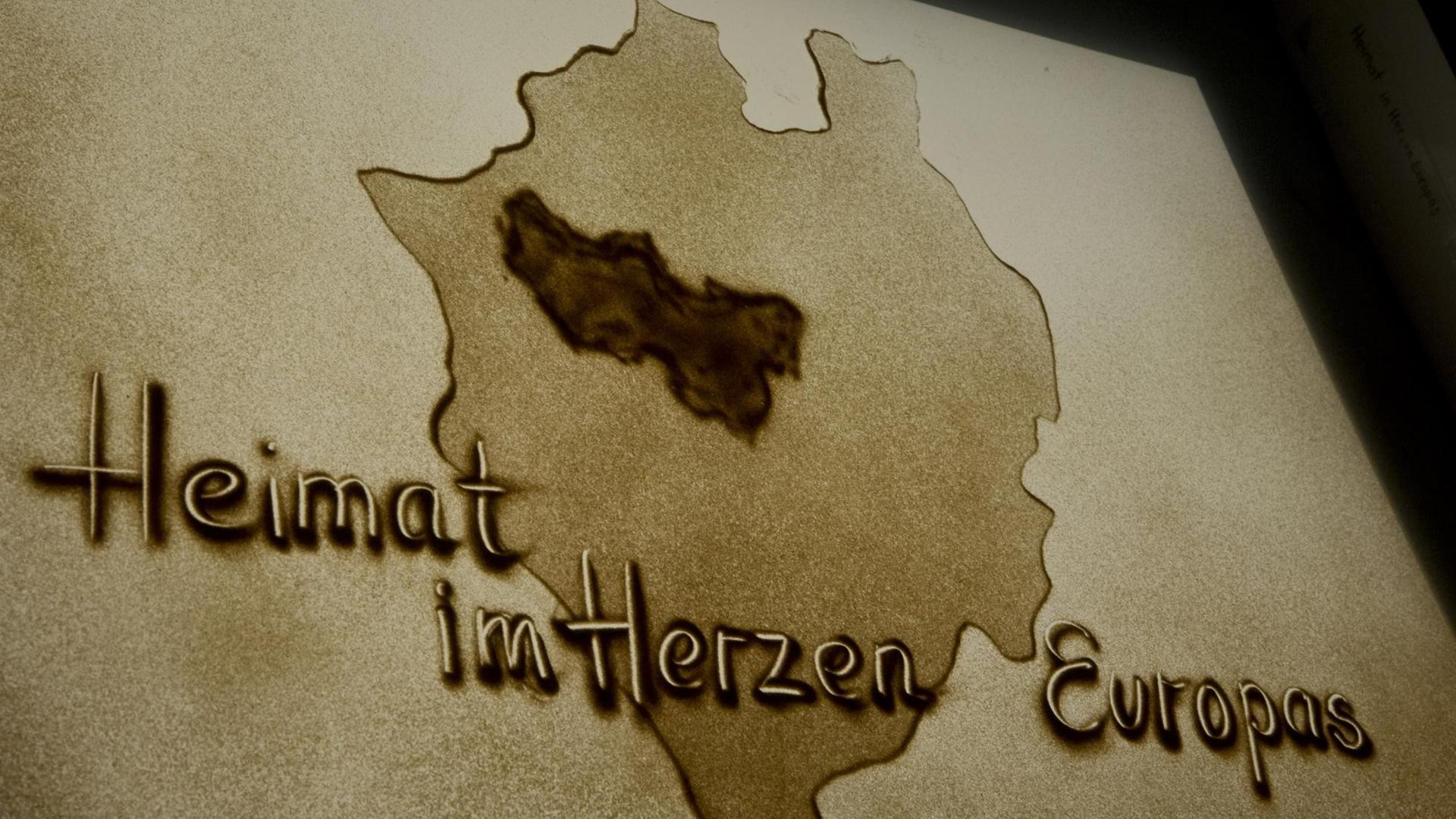 Die Umrisse von Nordrhein Westfalen mit der Schrift "Heimat im Herzen Europas" darauf, als Sandbild der Künstlerin Olga Lysytsky, auf einer Konferenz am Berufskolleg Bottrop. Die Umrisse von Nordrhein Westfalen mit der Schrift "Heimat im Herzen Europas" darauf, als Sandbild der Künstlerin Olga Lysytsky, auf einer Konferenz am Berufskolleg Bottrop.