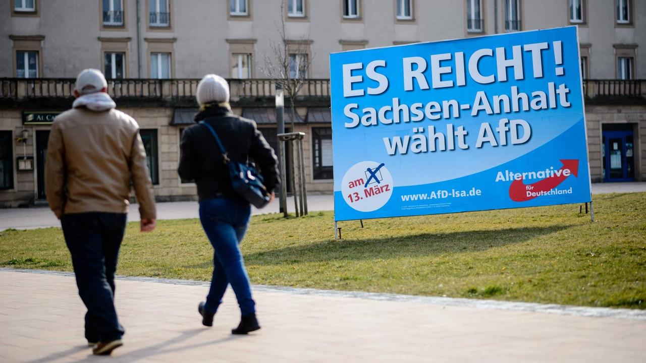 Zwei Menschen gehen in Merseburg in Sachsen-Anhalt an einem Wahlplakat der Alternative für Deutschland vorbei