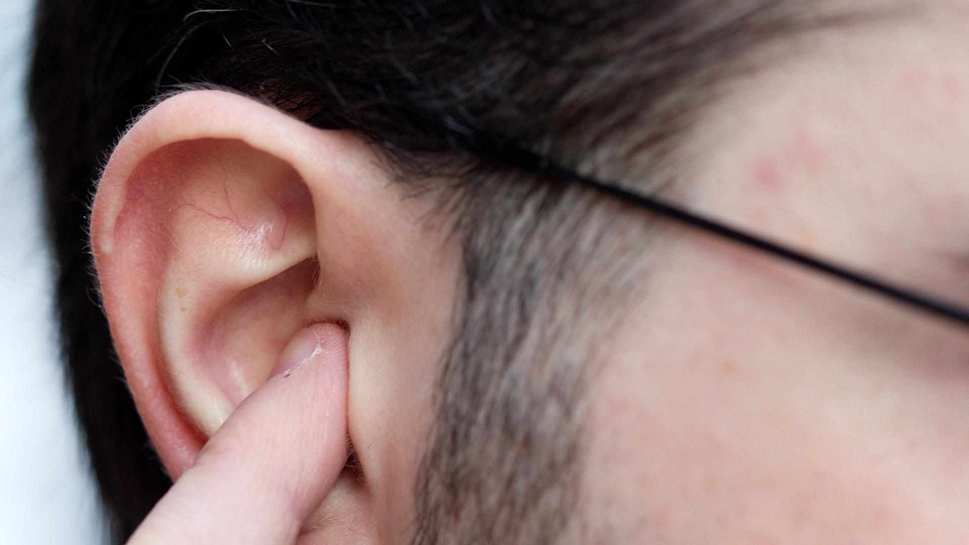 Ein Mann hält sich in Osnabrück als Gehörschutz einen Finger in das Ohr.