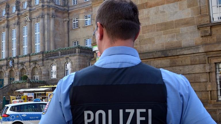 Ein Polizist steht am 16.05.2013 in Kassel (Hessen) vor dem wegen einer Bombendrohung abgesperrten und evakuierten Rathaus.