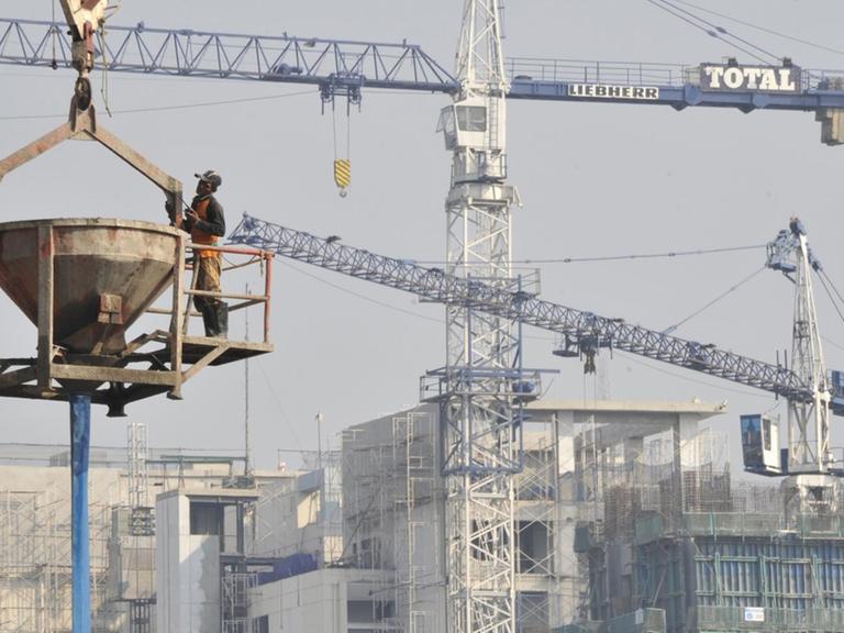 In der Luft hängend bereitet sich ein Arbeiter darauf vor, auf einer Baustelle für ein Bürohochhaus in Jakarta Zement zu gießen.
