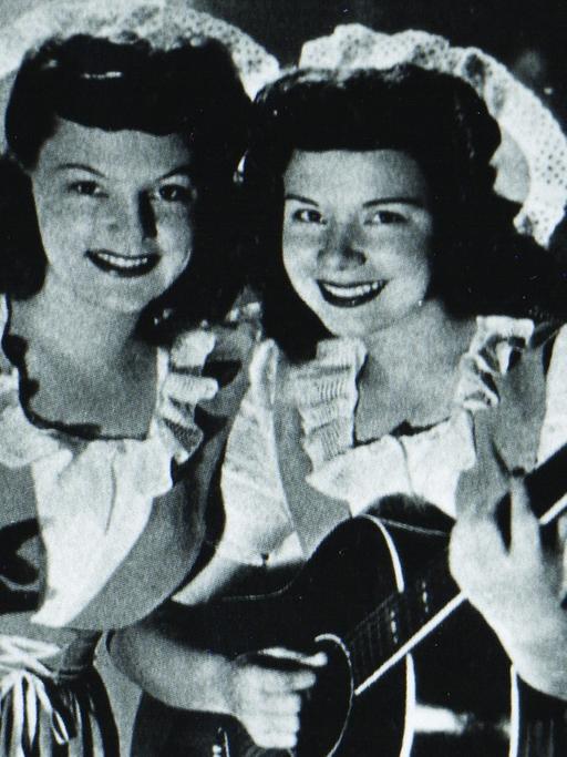 historische schwarz-weiß Fotografie mit den DeZurik Sisters in stilisierten Dirndln und mit einer Country-Gitarre