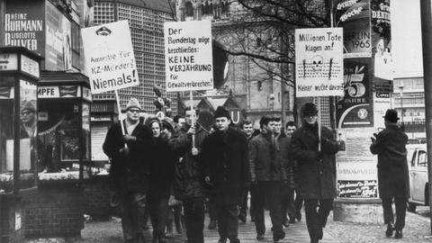 Demonstranten mit Schildern in der Hand protestieren am 6. Februar 1965 in Berlin gegen eine Verjährung von Mord und Völkermord
