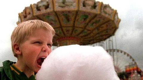 Ein Junge genießt Zuckerwatte auf der Düsseldorfer Kirmes