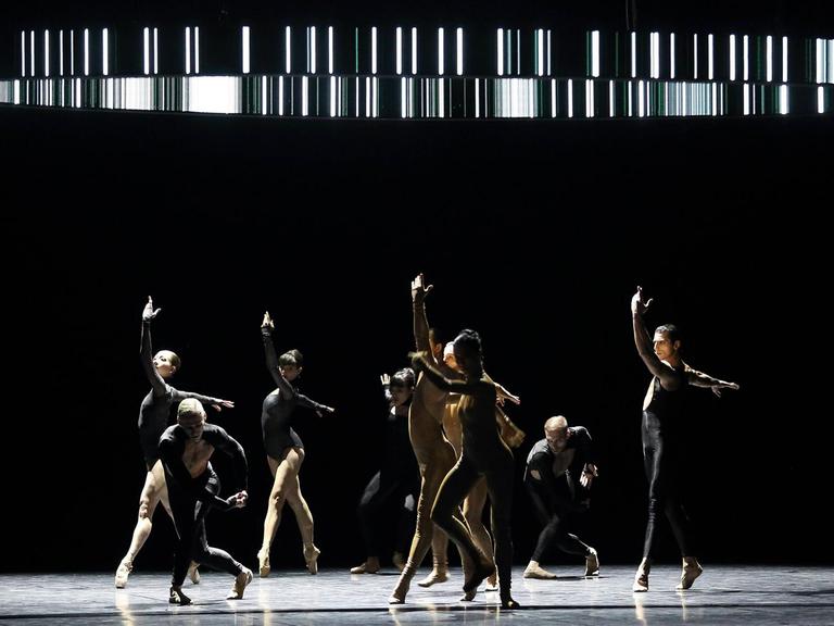 Mehrere Ballett-Tänzerinnen und Tänzer unter einem Lichtkreis