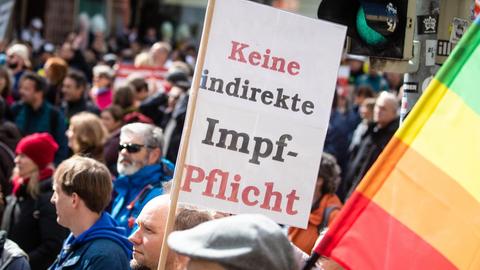 Ein Mann trägt auf einer Demonstration der Initiative «Querdenken» ein Schild mit der Aufschrift «Keine indirekte Impf-Pflicht». Die Demonstration richtet sich gegen die Pandemie-Einschränkungen der Bundesregierung - Abstandsregeln und das tragen von Masken wurde größtenteils missachtet.
