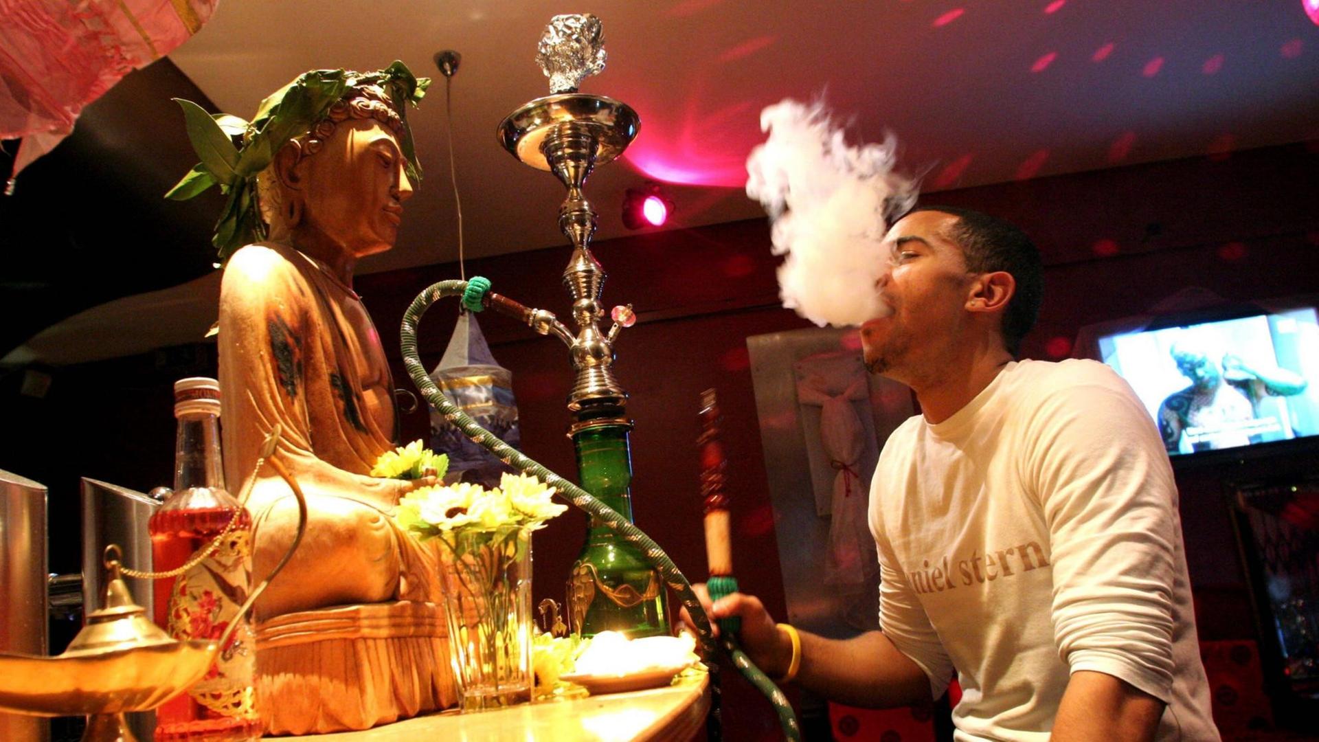 Junger Mann raucht Wasserpfeife in der Shisha-Lounge der Bar CREAM in München