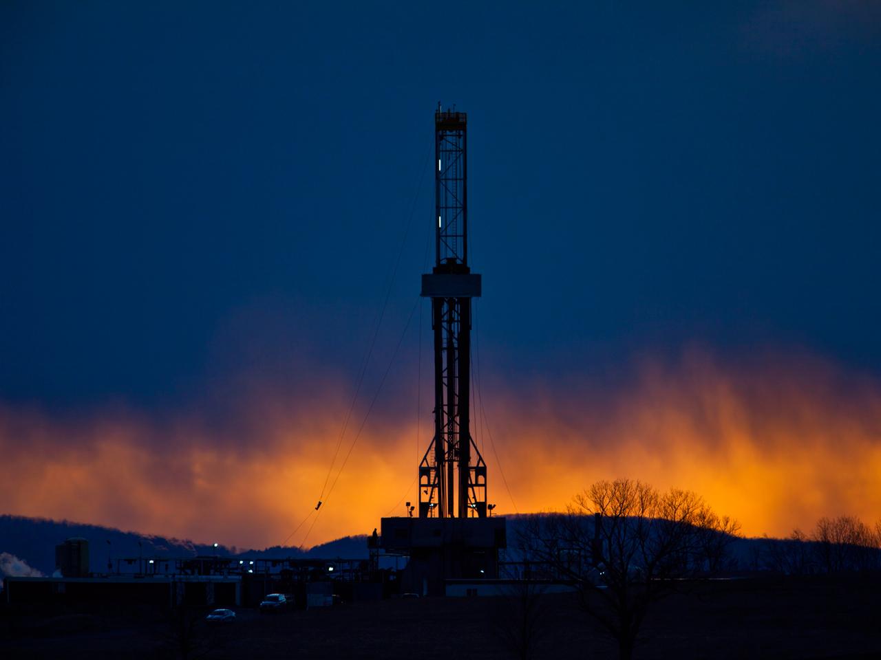 Ein Fracking-Bohrturm in der Abenddämmerung. 