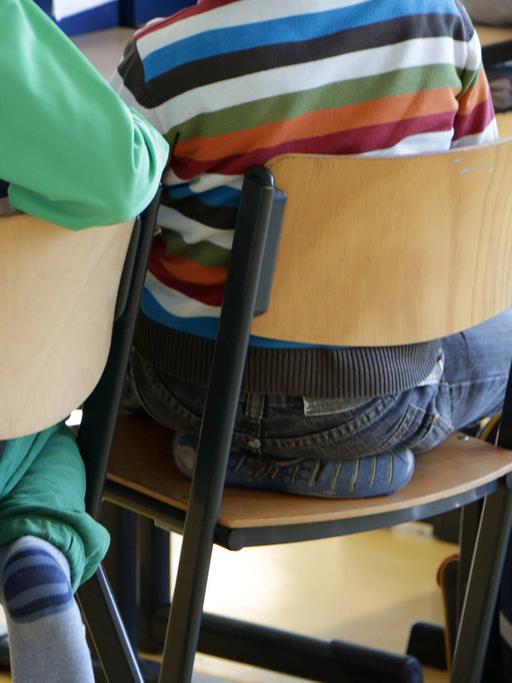 Schüler sitzen in der Klasse (Blick auf die Stühle und die Rücken der Schüler)