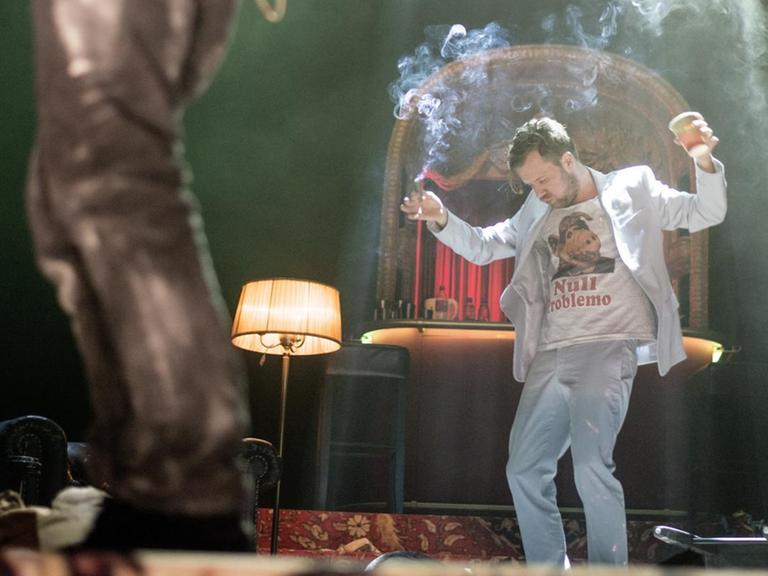 Der Schauspieler Nico Holonics hat in der einen Hand einen Bierbecher, in der anderen einen rauchenden Joint, Auf seinem T-Shirt steht "Null Probleomo".