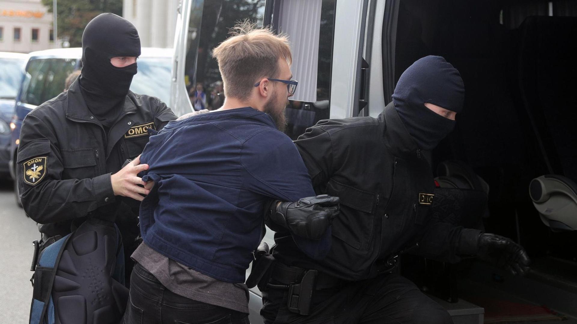Polizeikräfte nehmen bei Protesten in Minsk einen Studenten fest und schieben ihn in einen Transporter.