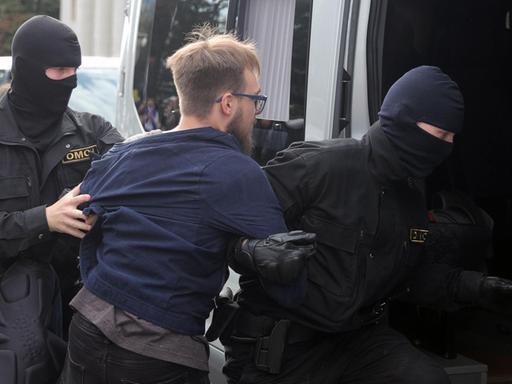 Polizeikräfte nehmen bei Protesten in Minsk einen Studenten fest und schieben ihn in einen Transporter.