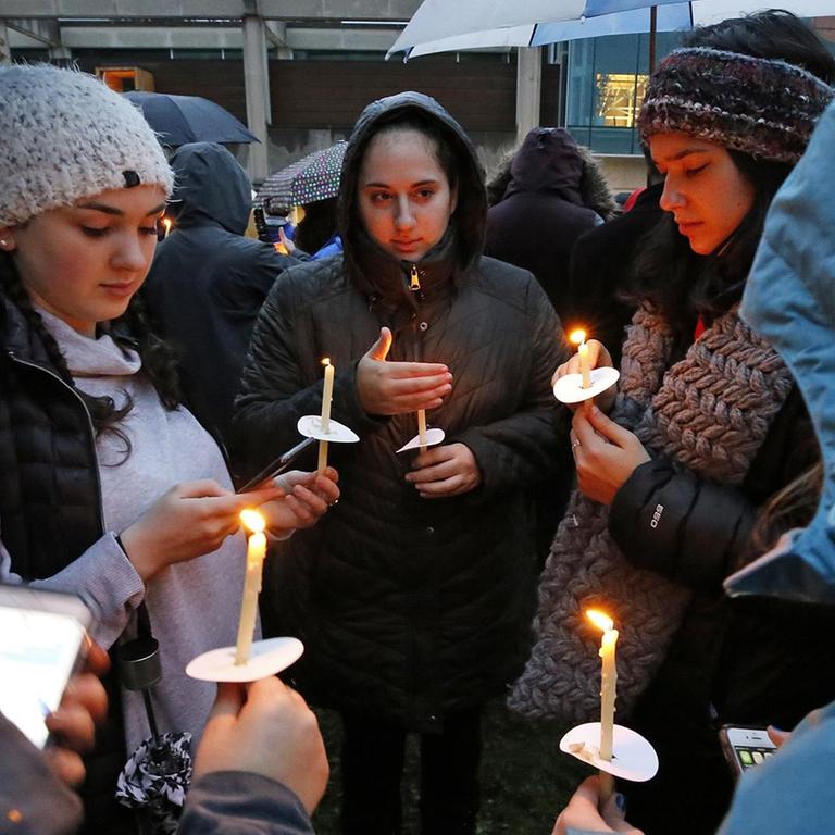 Mehrere junge Frauen warten in Pittsburgh auf den Beginn eines Gedenkgottesdienstes für die Opfer des Anschlags auf eine Synagoge. Sie stehen im Kreis und halten Kerzen in der Hand.