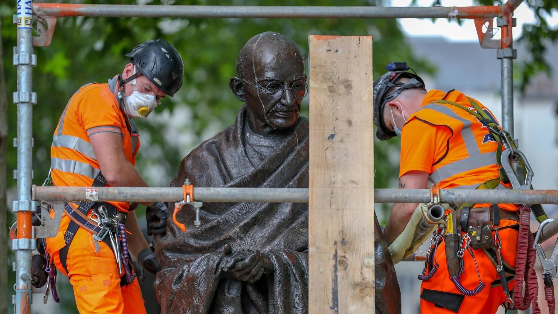 Arbeiter bauen vor einer Demonstration in London einen Schutz um die Statue des Friedensaktivisten Mahatma Gandhi.