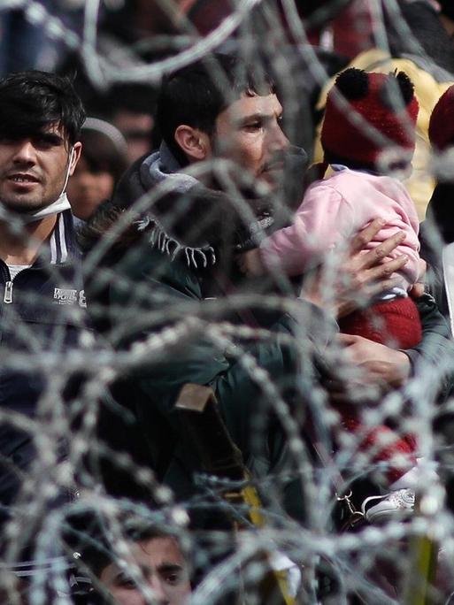 Migranten stehen am 2. März 2020 an der Grenze zwischen Griechenland und der Türkei an einem Stacheldrahtzaun.