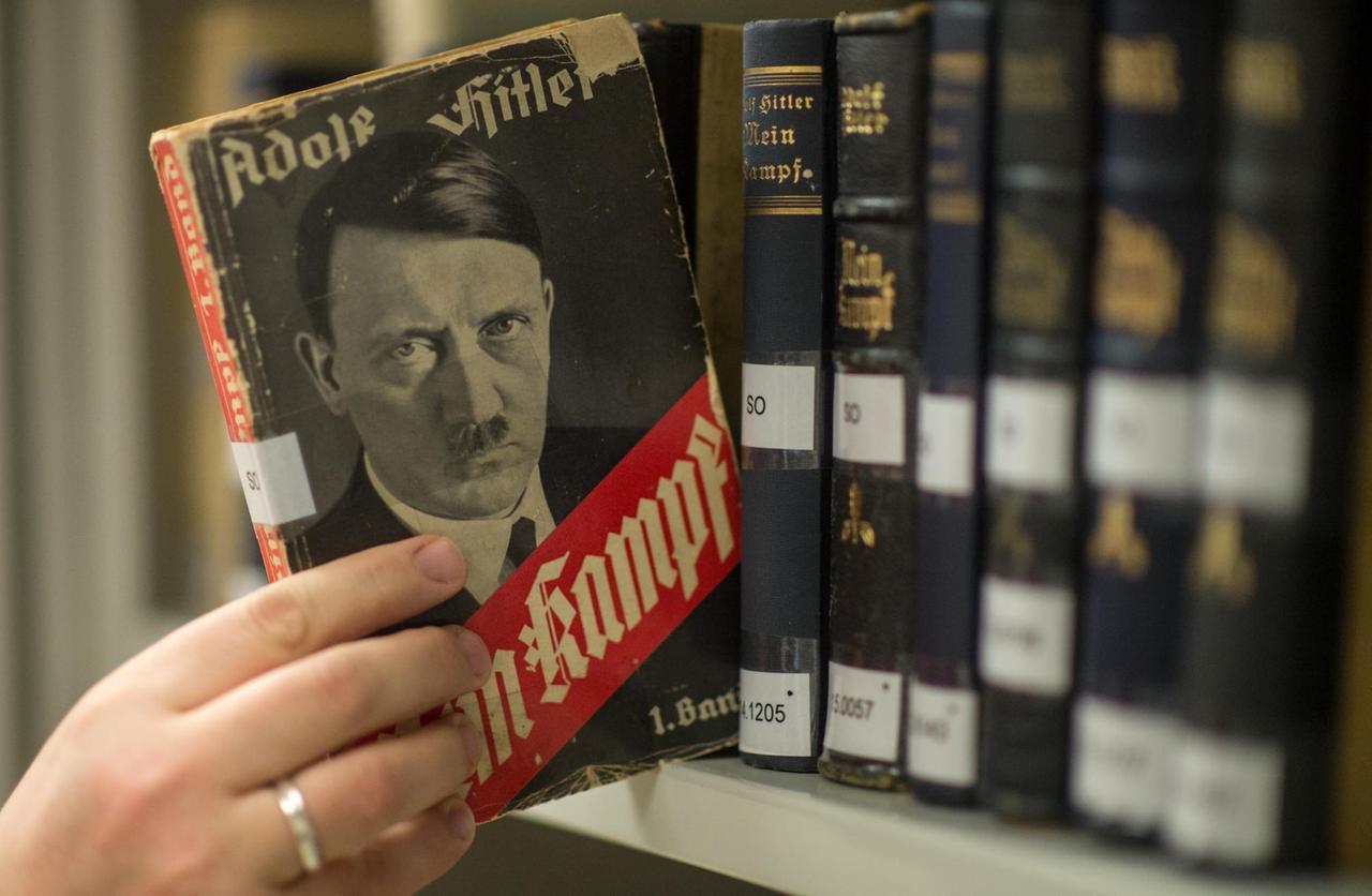 Man sieht, wie jemand eine Ausgabe von Hitlers "Mein Kampf" aus dem Jahr 1933 aus dem Regal zieht.