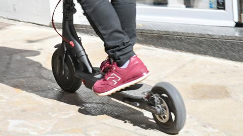 Die Beine eines Mannes auf einem E-Roller (Cityroller) in Palma de Mallorca.