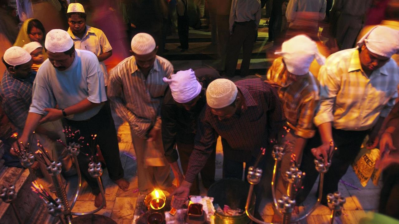 Indische Gläubige entzünden Kerzen in einem Sufi-Schrein. 
