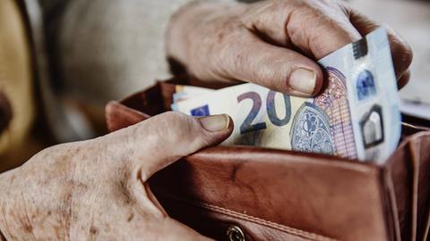 Eine Seniorin zieht einen 20 Euro Schein aus ihrem Portemonnaie.