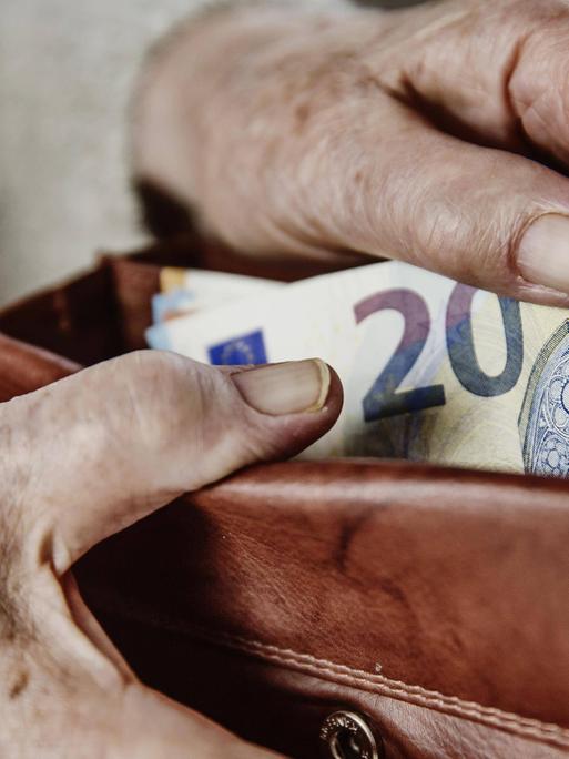 Eine Seniorin zieht einen 20 Euro Schein aus ihrem Portemonnaie.