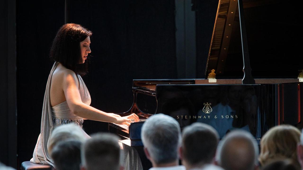 Alexandra Dariescu sitzt an einem großen Flügel und spielt. Sie trägt ein silbernes Kleid. Das Publikum hört aufmerksam zu. Das Konzert fand im Rahmen des Klavier-Festival Ruhr statt.